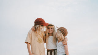 A group of kids embracing wearing vintage baseball caps by Will & Bear.