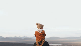 Child on a hike, wearing a Will & Bear hiking hat, gazes at distant peaks.