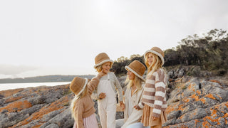 A family all in winter buckets hats by Will & Bear shares a joyous moment by the sea at sunset