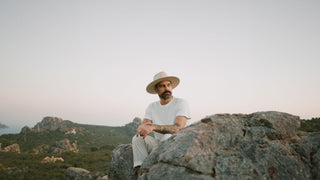 Man sits on a cliff at dusk wearing a white felt hat by Will & Bear Gat Co