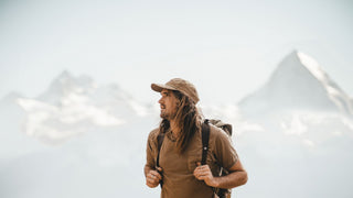 A male hiker in a hat by Will & Bear looks out over misty mountains, embodying a hiking hat adventure.
