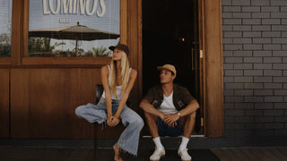 Man and woman at the beach hugging and the man wearing a mens Will & Bear cap
