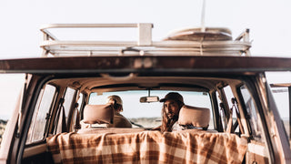 A close-up of a brown vintage dad cap by Will & Bear, placed next to camping gear.