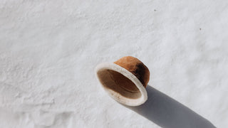 A winter bucket hat by Will & Bear lies on fresh snow, casting a long shadow in the bright sunlight.