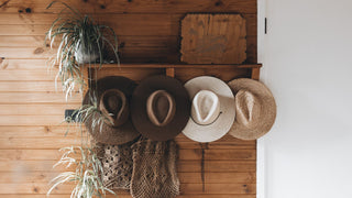 Straw hats hanging on a wall in a rustic cabin ready for the beach