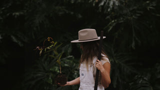 A women in a beige Will & Bear gardening hat planting a tree.