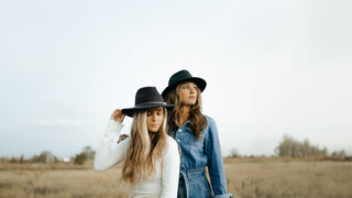 Two women gaze into the distance, adorned with fedora hats by Will & Bear, embodying a blend of modern and classic style.