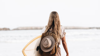 Woman carrying a wide brim hat using a hat carry clips accessories attached to her bag