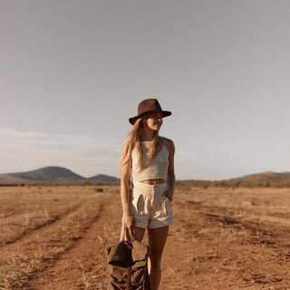Woman standing in open field with Anderson Brown hat and linen outfit