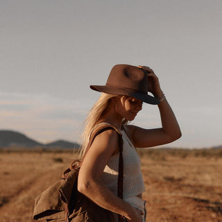 Woman wearing Anderson Brown hat and backpack in desert landscape