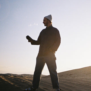 Man wearing the Will & Bear Bambi Dust Blue Australian wool beanie on a sunset hike, ideal for travel and cool climates.
