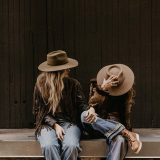 Two women with Will & Bear Wide Brim Country Hats sitting on a timber step, sharing a relaxed moment.