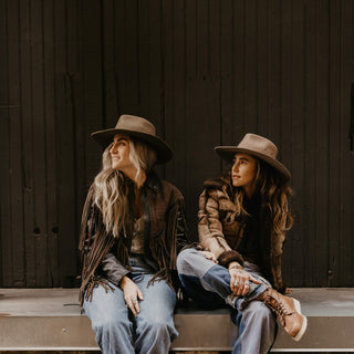 Two women wearing Will & Bear Brown Country Hats, sitting outdoors in casual country-style outfits