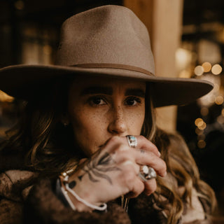 Cozy indoor scene with woman wearing Will & Bear Brown Country Hat, perfect for winter escapes