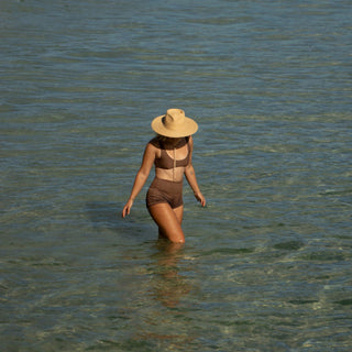 Woman wading in shallow water wearing Will & Bear straw sun hat for eco-friendly sun protection