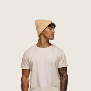 Man wearing Will & Bear Bambi Apricot merino wool beanie with minimalist white background for fit reference.