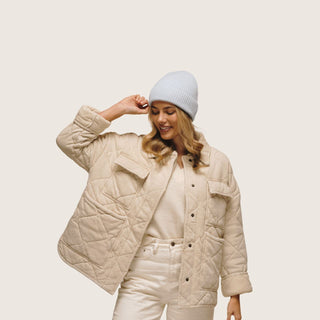 Woman adjusting the Will & Bear Bambi Dust Blue Australian wool beanie in soft studio lighting.