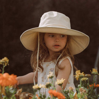 Girl wearing Will & Bear Kids Packable Bucket Hat in a flower garden, offering breathable sun protection.