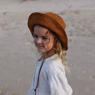 Young Girl Wearing Will & Bear Kids String Bucket Hat – Comfortable and Protective Bucket Hat in Rust Orange.