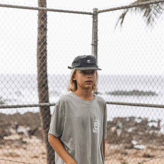 Boy Wearing Will & Bear Kids Black Cap – Classic Everyday Cap for Children by the Coast.