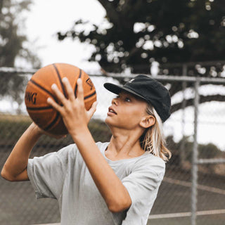 Child Shooting Hoops in Will & Bear Kids Black Cap – Adventure-Ready Cotton Cap for Active Kids.
