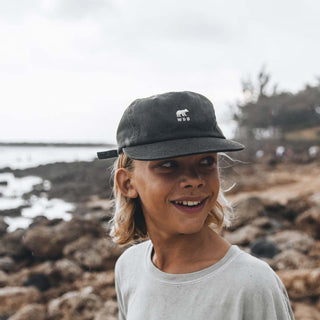Boy Wearing Will & Bear Kids Black Cap by the Beach – Lightweight and Breathable Kids Cap.
