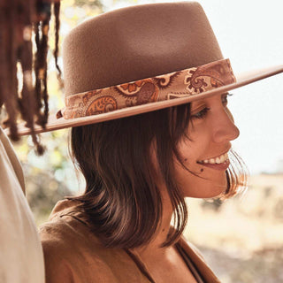 Woman wearing a hat adorned with the Will & Bear Hat Scarf Hazel, styled in a loop with the scarf as the focal detail.