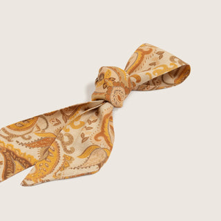 Close-up of the Will & Bear Hat Scarf Mustard tied in a bow, highlighting soft fabric texture and detailed print.