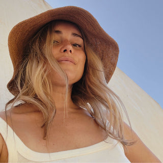 Close-up of woman smiling while wearing Will & Bear Women's Straw Bucket Hat, designed for sun-filled adventures