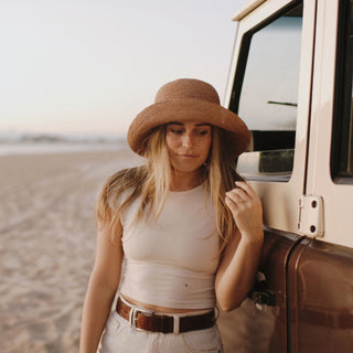 Woman wearing Will & Bear Women’s Straw Bucket Hat – Sunny Husk – relaxed coastal style for sun-filled beach days.