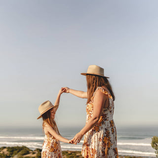 Mum and daughter wearing Will & Bear Little Calloway Cream Fedoras dancing on a cliff by the sea.