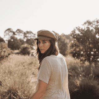 Woman in a field wearing the Will & Bear Baker Tan corduroy bakerboy cap.