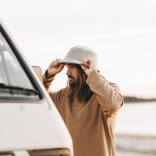 Man Adjusting Will & Bear Perry Bone Beige Cord Bucket Hat – Road Trip Vibes in Cord Headwear.