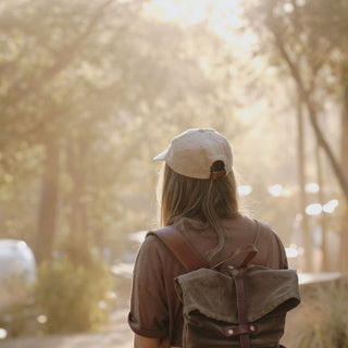 Woman Wearing Will & Bear Parker Bone Beige Cord Dad Cap – Outdoors Walking with Backpack.