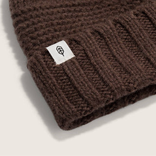 Close-up of Will & Bear Brown Pom Pom Beanie – Tasman Brown – detailing thick ribbed cuff and branded patch.