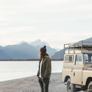 Man with long hair wearing Will & Bear Brown Pom Pom Beanie – Tasman Brown – rugged cold-weather accessory for outdoor explorers.