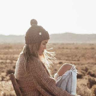 Woman in Will & Bear Brown Pom Pom Beanie – Tasman Brown – cozy headwear for cool days in nature.