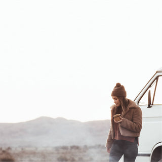 Woman in Will & Bear Brown Pom Pom Beanie – Tasman Brown – road-trip-ready warmth with natural materials.