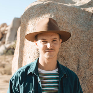 Man wearing Will & Bear Brown Wide Brim Fedora in rugged desert landscape