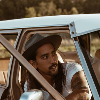 Man styled in the Will & Bear Calloway Ash wide brim felt fedora, leaning from a vintage car window.