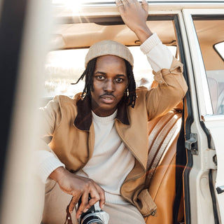 Man relaxing inside a car wearing the Will & Bear Doc Fawn Wool Fisherman’s Beanie, styled for a cool-weather road trip.