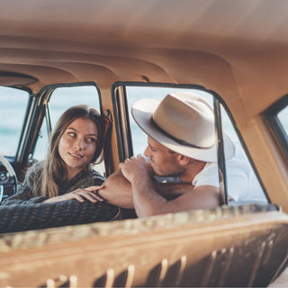 Couple smiling during adventure, wearing Will & Bear Felt Fedora Hats inside classic car