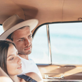 Road trip moment with man and woman wearing Will & Bear Felt Fedora Hats, captured in vintage car