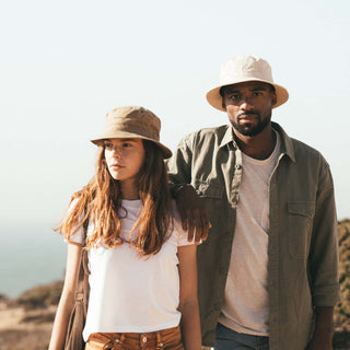 Man and woman standing together wearing Will & Bear Fischer Bone White Bucket Hats, styled for beachside travel.