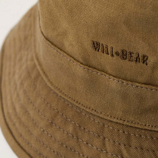 Close-up of the Will & Bear Fischer Sand Waxed Canvas Bucket Hat showing branded embroidery and fabric texture.