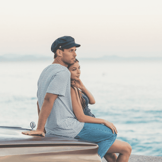 Man wearing the Will & Bear Foster Black Newsboy Cap by the ocean, styled with a short-sleeve shirt and relaxed fit.