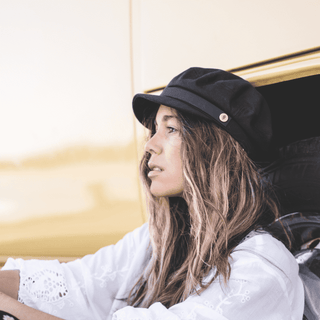 Woman wearing the Will & Bear Foster Black Newsboy Cap, styled casually while seated in a classic car.