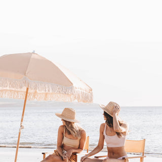 Friends in Will & Bear Men's and Women's Straw Hats sitting beachside under umbrella, built for summer