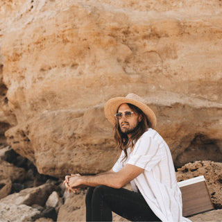Relaxed moment with man wearing Will & Bear Men's and Women's Straw Hat beneath sunlit cliff