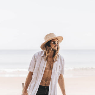 Man walking by the ocean in Will & Bear Men's and Women's Straw Hat, styled for coastal escapes
